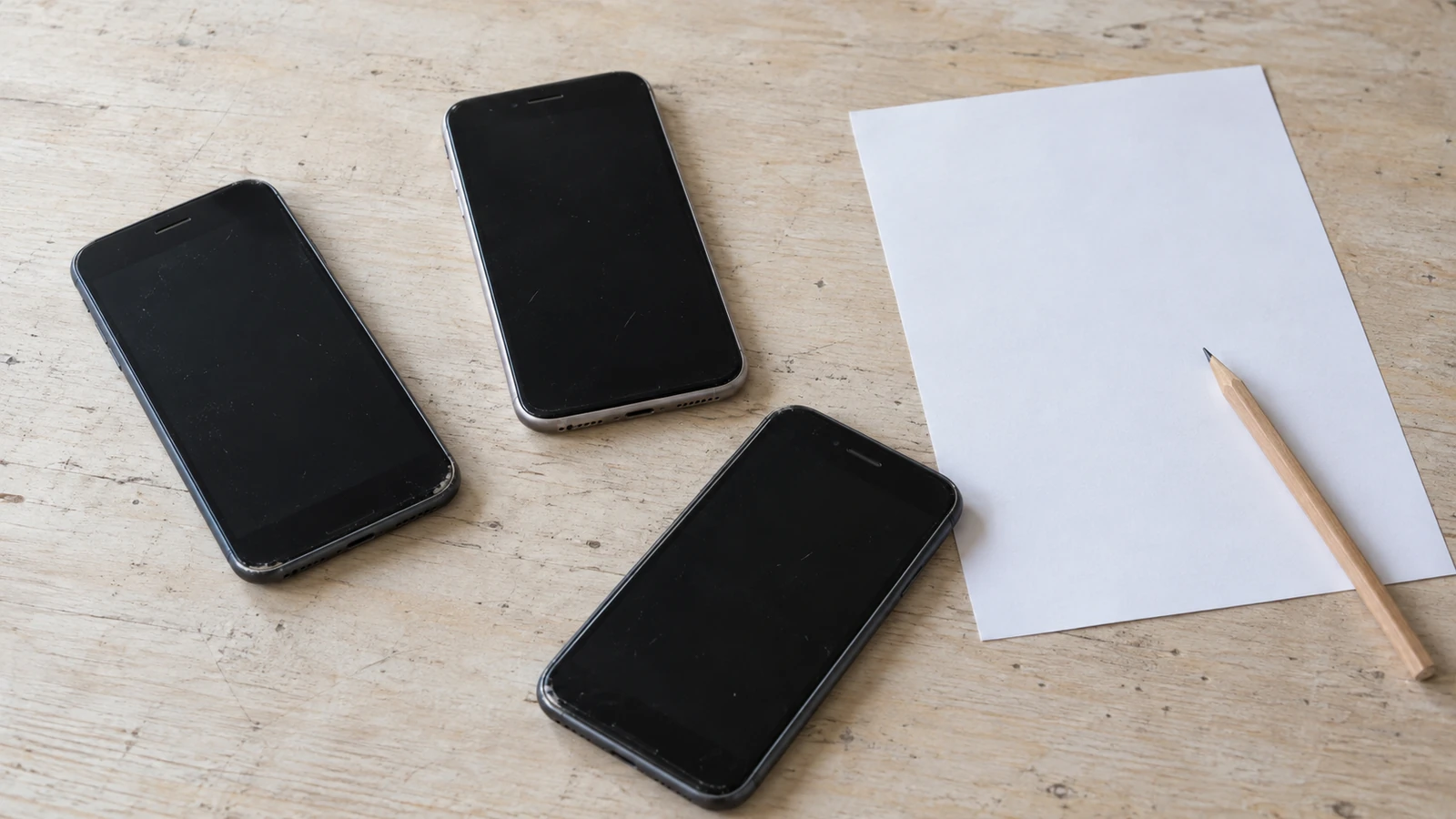 Several used phones with dark screens beside a blank condition-record sheet
